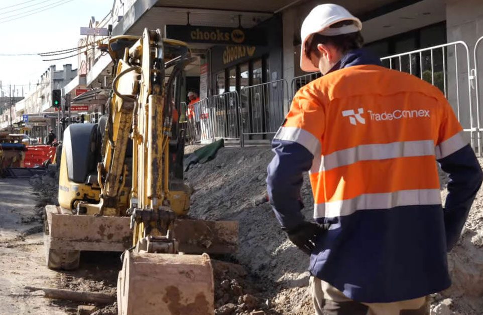 Construction worker in safety gear on a job site helping with heavy machinery