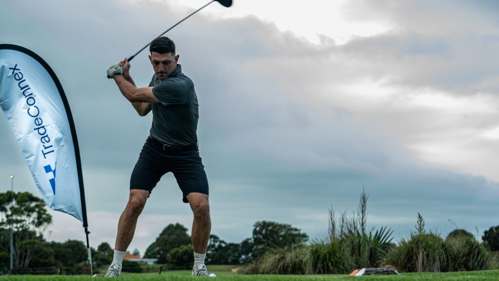 A golfer teeing off at the TradeConnex Golf Invitational